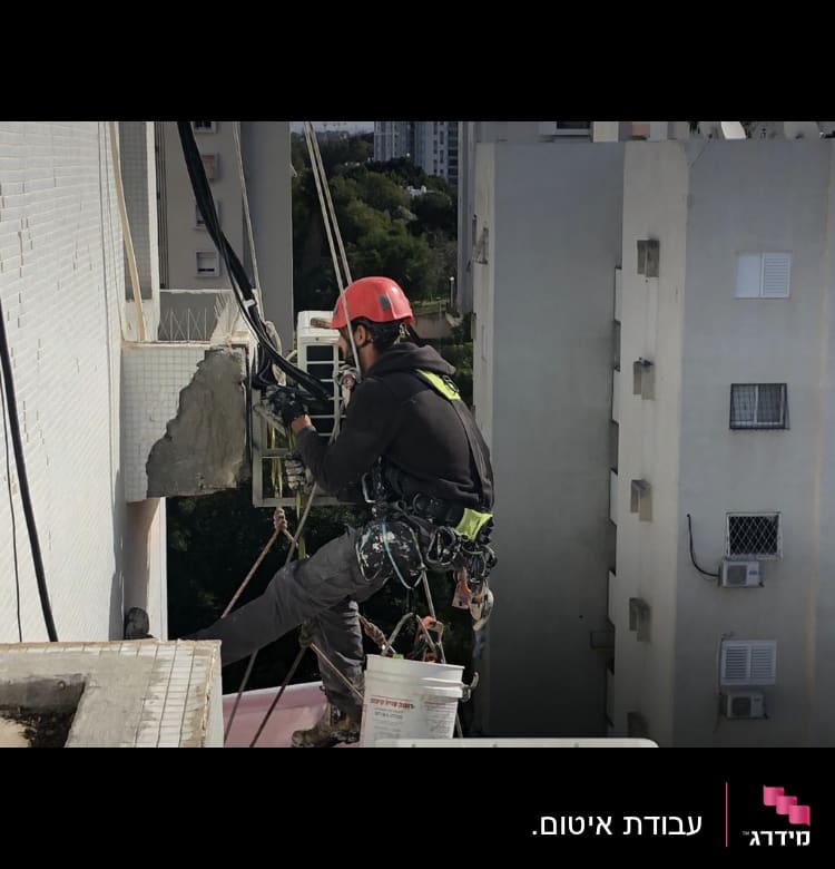 אדם עם קסדה אדומה עובד על איטום קיר חיצוני